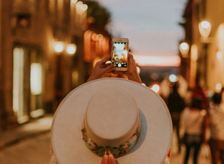 Back view of a person photographing sunset in San Miguel de Allende with a smartphone.